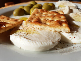 Sliced mozzarella with crackers, olive oil, pepper, salt and olives. Light snack of crackers and cheese.