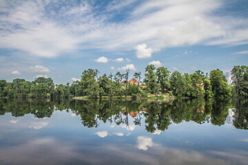 Fototapeta premium Lake, with forest around it, an some old damaged buildings seen in the distance