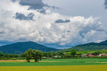 Obraz premium The green Black Forest mountains viewed from the valley in Bühl, Germany, on a summer day with some rainy clouds