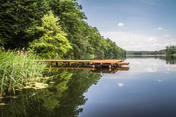 Obraz premium Lake with a small wooden bridge on a warm day 