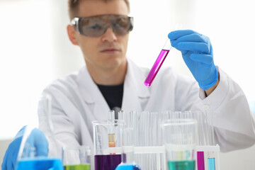 A male chemist holds test tube of glass in his hand overflows a liquid solution of potassium...