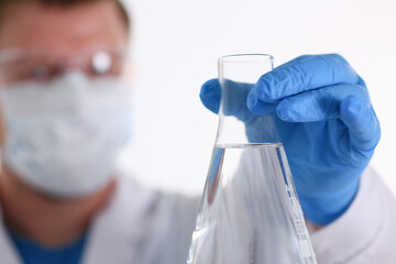 A male chemist holds test tube of glass in his hand overflows a liquid solution of potassium...