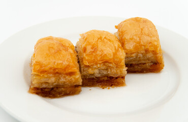 three slices of Turkish baklava on a white plate, close up