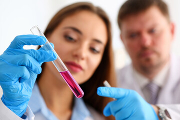 Female technician arms in protective gloves hold fluid sample bottle closeup. Medical worker in...
