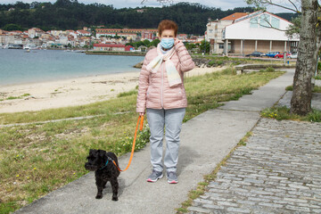 senior woman with medical mask walking dog