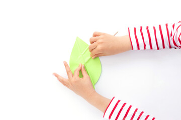 kids hands push strips on a green leaf shape paper detail, simple paper craft for kid and kindergarten, step by step instruction, tutorial, DIY, snail project, step4, stick © Elena