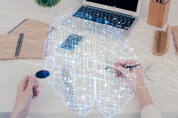 Double exposure of woman's writing hand on background with brain hud. Concept of learning.
