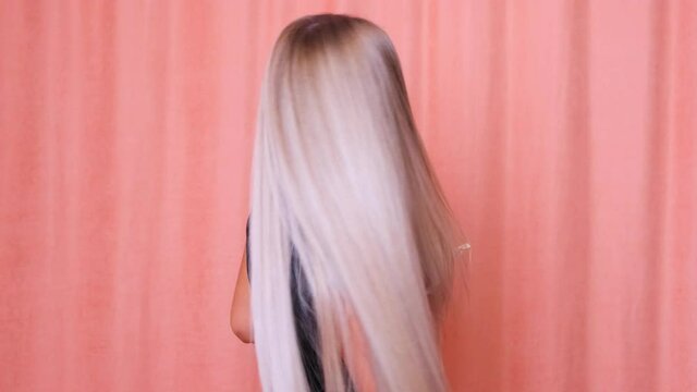 Beautiful female with healthy long straight blond hair. Dyed wavy white blond hair background, dyeing, extensions, treatment, treatment concept. Hair care. Slow motion 4K UHD video