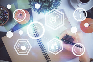 Social network theme hologram over hands taking notes background. Concept of global international people connect. Double exposure