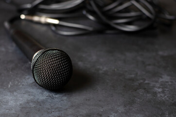 Obraz premium Black microphone on a dark concrete background. Equipment for vocals or interviews or reporting. Copy space