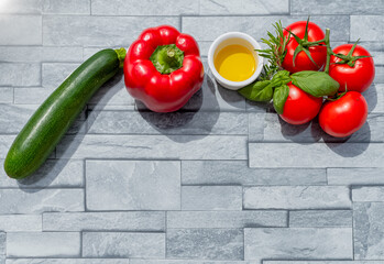 Présentation créative de légumes de saison de l'été avec tomates, courgette, poivron rouge, huile d'olive et basilic frais. Sur fond pour inclure un texte.