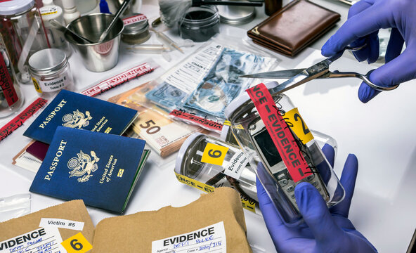 Scientific police opens with scissors a bag of evidence of a crime in scientific laboratory