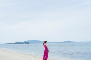 Fototapeta na wymiar リゾートで海沿いを歩く女性