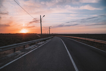 Attractive fit man running along modern bridge at sunset light,