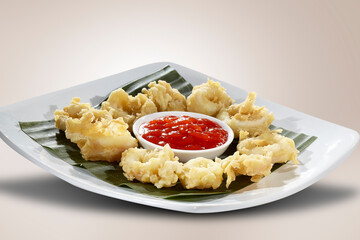 Calamari or squid flour or Oven Fried Onion Rings, served with chili sauce, on a plate of banana leaf.