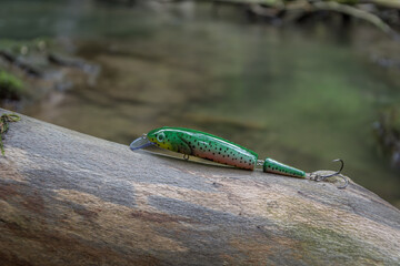 Colorful fishing hook, plummet and baits for catching fish on wet wood trunk background. Fishing and hobbies concept, close up