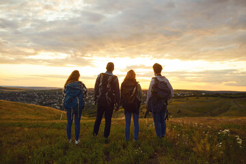 A group of people tourists stand at sunset on the nature.
