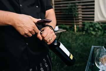 Sommelier opening a wine bottle at a wine tasting party, outdoors.