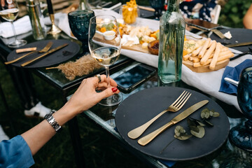 Woman holding a glass of white wine at an open air party at a restaurant terrace. 