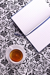 a white ceramic cup with tea and lemon slice on vintage trendy pattern natural textile surface