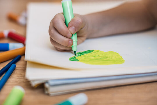 child's hand drawing a tree with colored markers