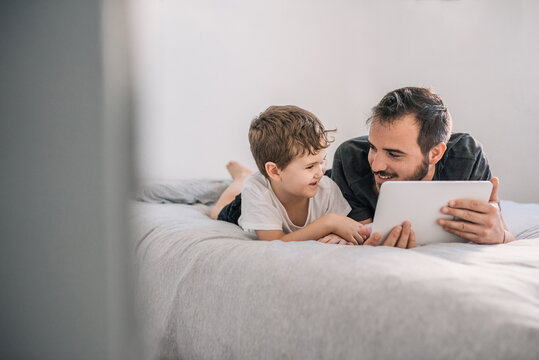 boy (6-7 years old) with his father watching cartoons on a tablet and smiling