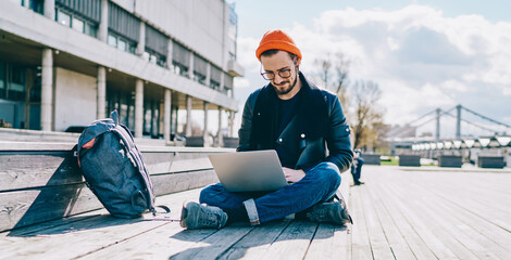 Stylish caucasian male blogger updating software on laptop computer for installing new application...