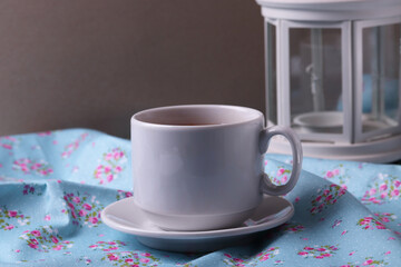 a white ceramic cup with tea and lemon slice on vintage trendy pattern natural textile surface