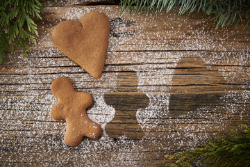 Loneliness during Christmas, a lonely gingerbread with the contour of another lying on wooden boards