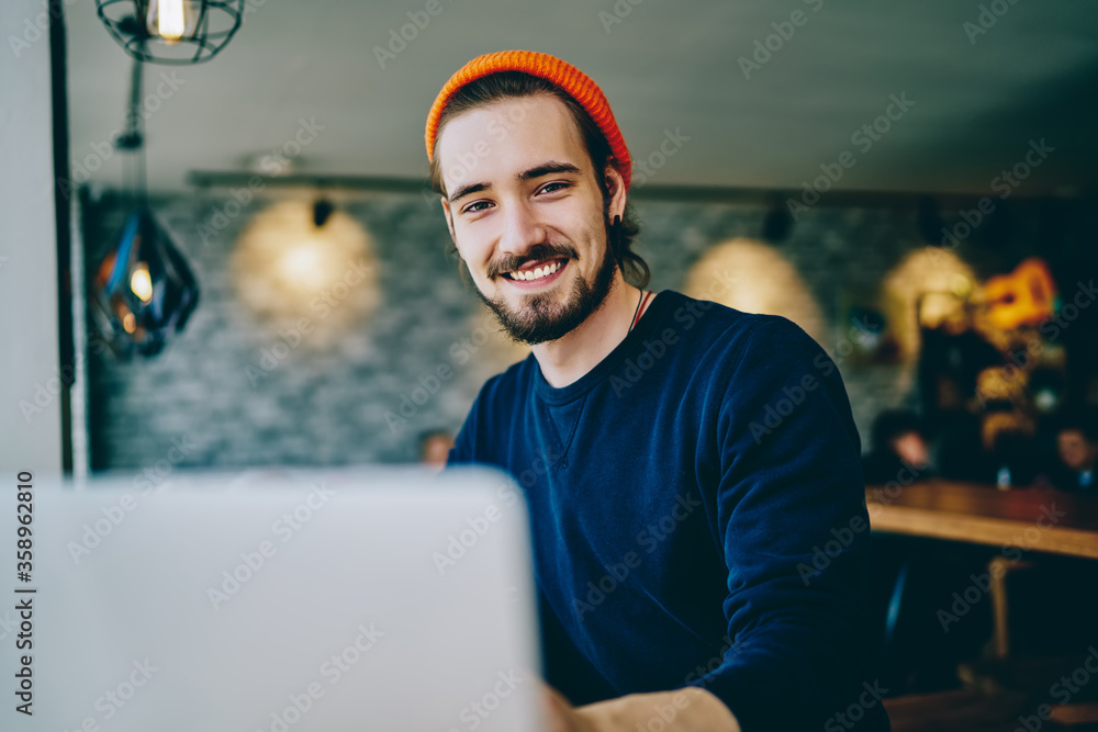 Poster portrait of cheerful caucasian man in trendy bennie satisfied with online language courses using net
