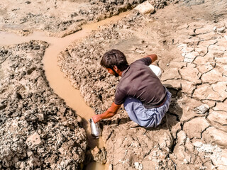 a teenager is poring dirty water into his jug cause of drinking water crisi