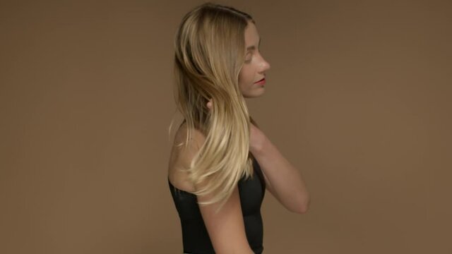 blonde young woman with long hair shake her head and hair blowing in air Profile portrait in studio slow motion from 120 fps