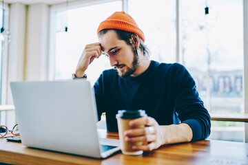 Caucasian male student feeling tired while watching boring training webinar on web page via laptop...