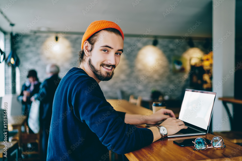 Poster skilled male it developer looking at camera using blank modern laptop computer working on freelance 