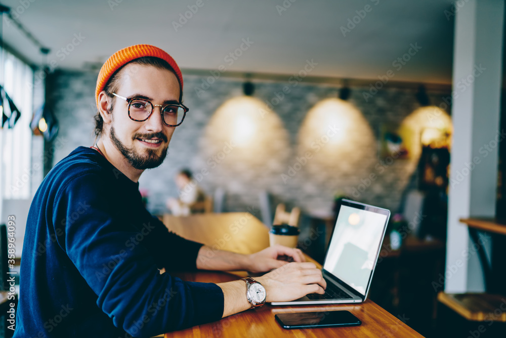 Poster portrait of happy male freelancer in optical eyewear for vision correction smiling at camera during 