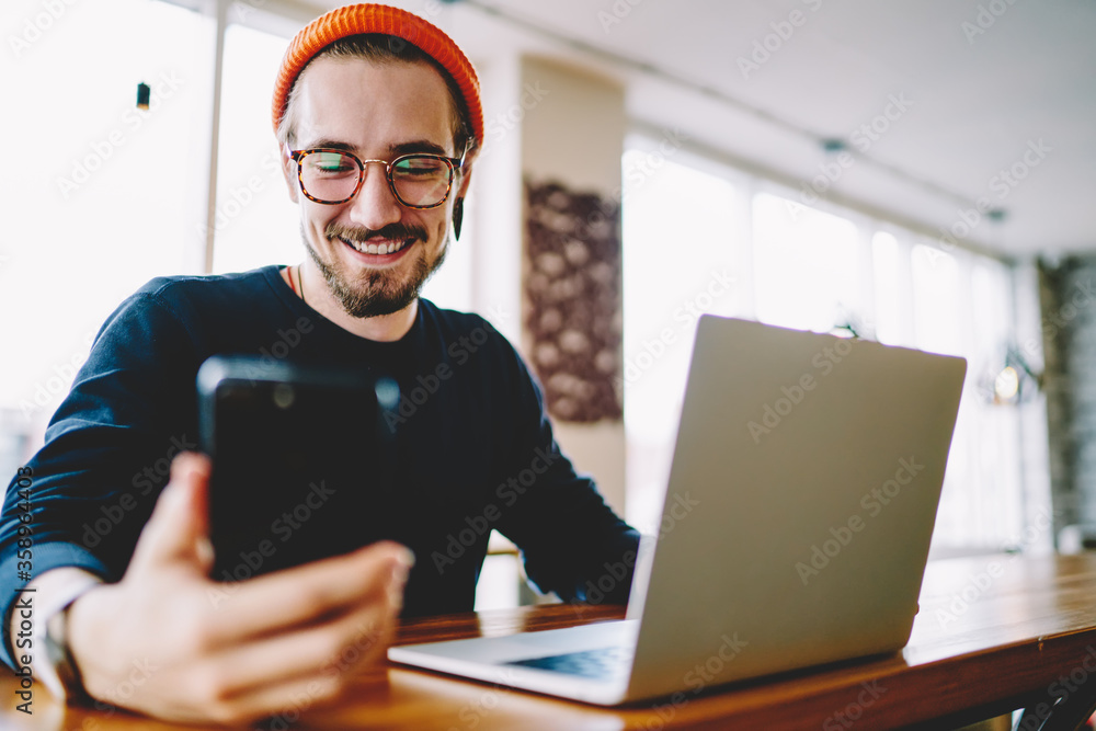 Poster happy caucasian freelancer reading positive web publication on cellphone technology smiling during w
