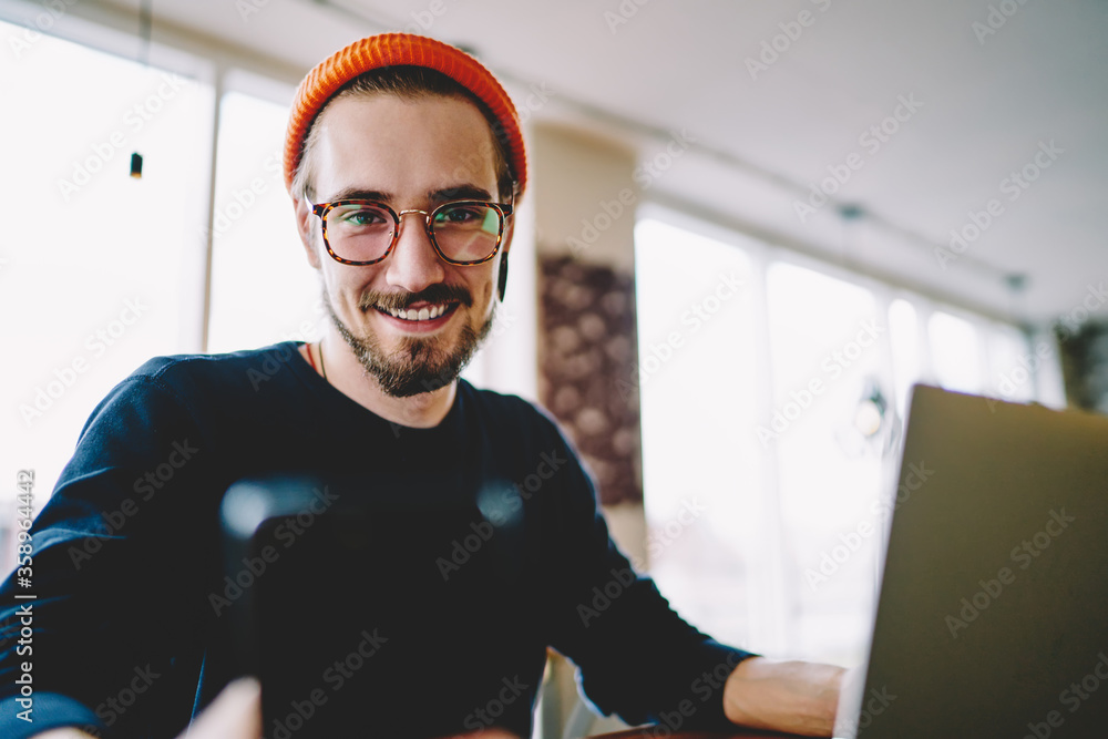 Poster portrait of prosperous male freelancer satisfied with online business working remotely on laptop com