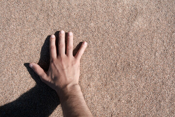 Hand touches quartz sand. Point of view.