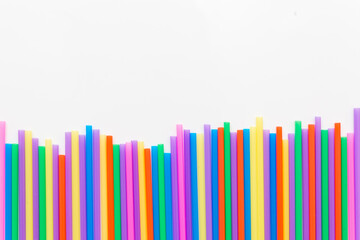 A strip of many plastic colored straws arranged in a row. Isolated