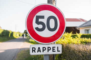 Round 50 kilometers per hour speed limit road sign in town. Written in french 