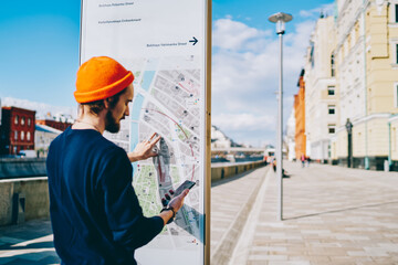 Youthful tourist installing application with city map for tracking gps during touristic sightseeing...