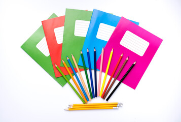 Colorful school exercise books and drawing pencils on white background.