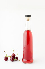 Bottle of cherry drink and heap of cherries on the white background