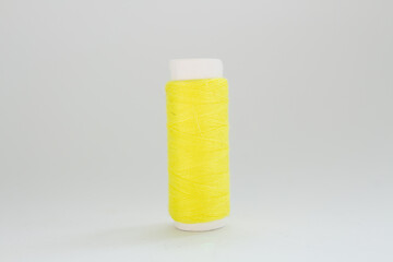 spool of yellow thread on a white background