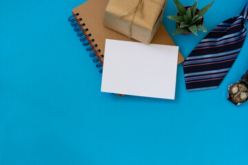Happy father's day. Flat top layout with congratulations, men's striped tie, box wrapped in kraft paper, a clock, a notebook, a sheet for text, a succulent flower