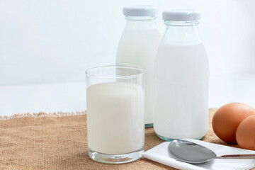 Bottle of milk with a glass of milk and eggs on the sackcloth with white background. Healthy food for breakfast concept.