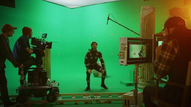 Director Commands Camera Operator to Start shooting Green Screen CGI Scene with Actor Wearing Motion Tracking Suit and Head Rig. Big Film Studio Professional Crew Shooting Blockbuster Movie