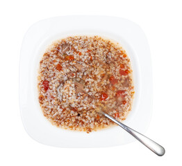 top view of buckwheat soup in white soup plate with spoon isolated on white background