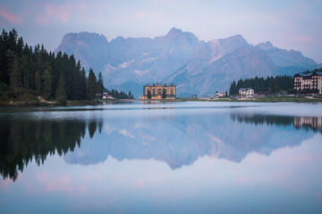 Reflection of seamless calm and still lake in Misurina, Italy with yellow building in front of mountains