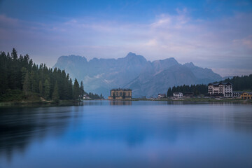 Fototapeta premium Reflection of seamless calm and still lake in Misurina, Italy with yellow building in front of mountains
